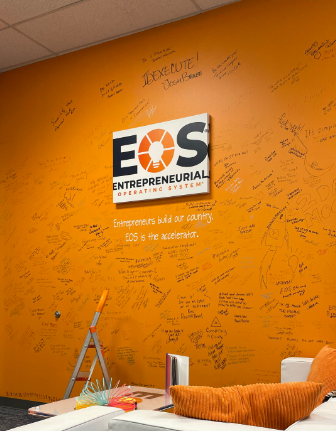 A bright orange wall featuring motivational notes left by EOS clients in the Dallas office