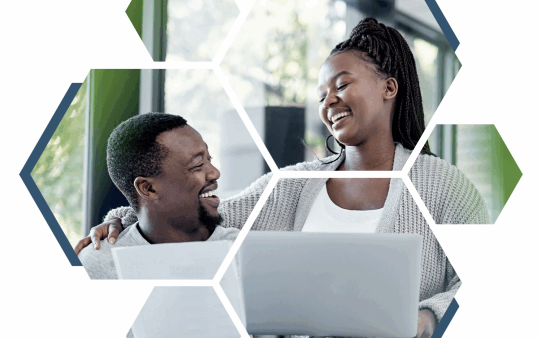 A happy couple laughs together as they look at something on a laptop screen