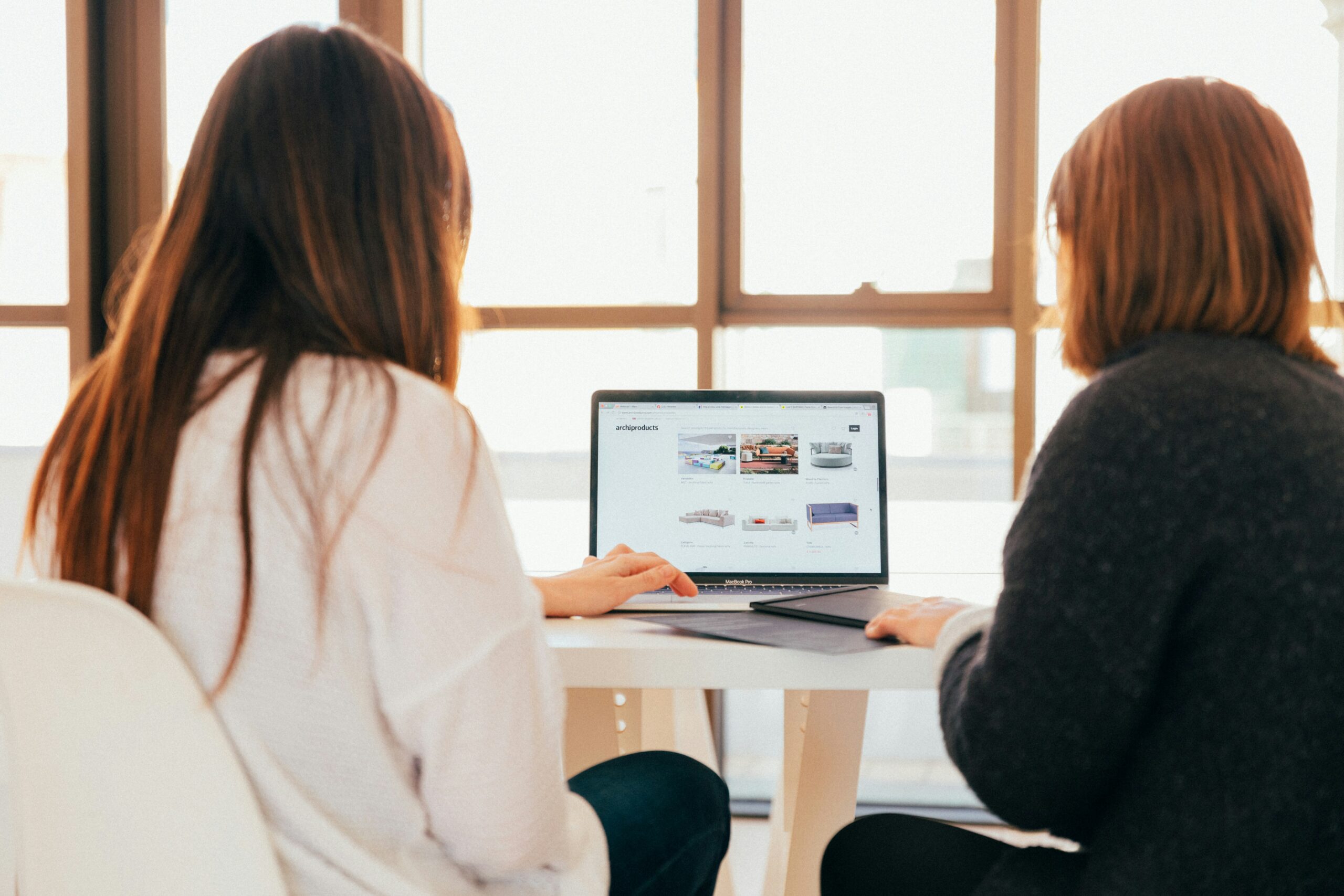 Two women look at a laptop trying to figure out how to deal with their student loans